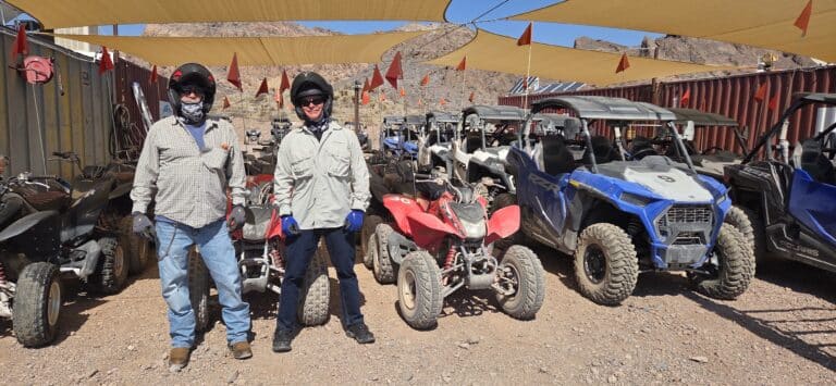 Two riders in helmets by ATVs at a Nevada desert rental near Las Vegas, perfect for RZR tours and off-road adventures.
