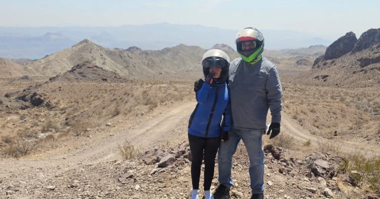 Two people in helmets and jackets pose on a Nevada desert trail near Las Vegas, perfect for ATV tours or RZR rides.
