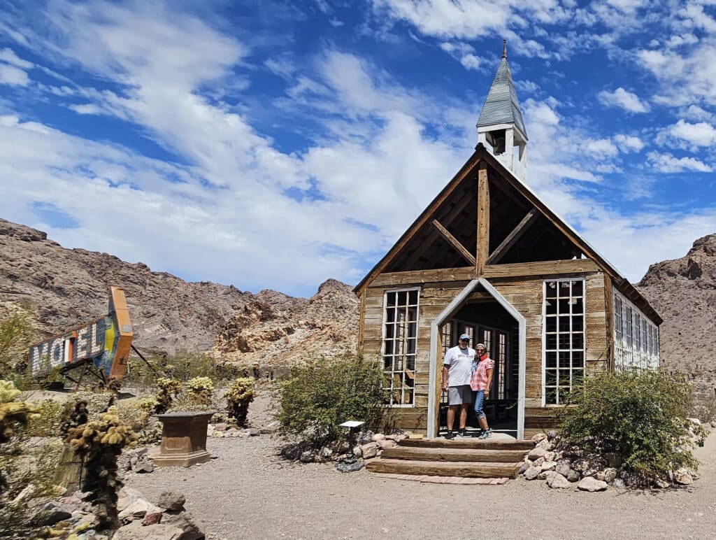 Two people at a rustic Nevada chapel near Las Vegas, desert backdrop, vintage motel sign—perfect for Ghost Town sightseeing tours.