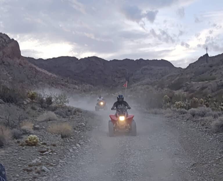 Riders on ATVs explore a dusty Nevada desert trail near Las Vegas at dusk, perfect for thrilling ATV tours and RZR off-road adventures.