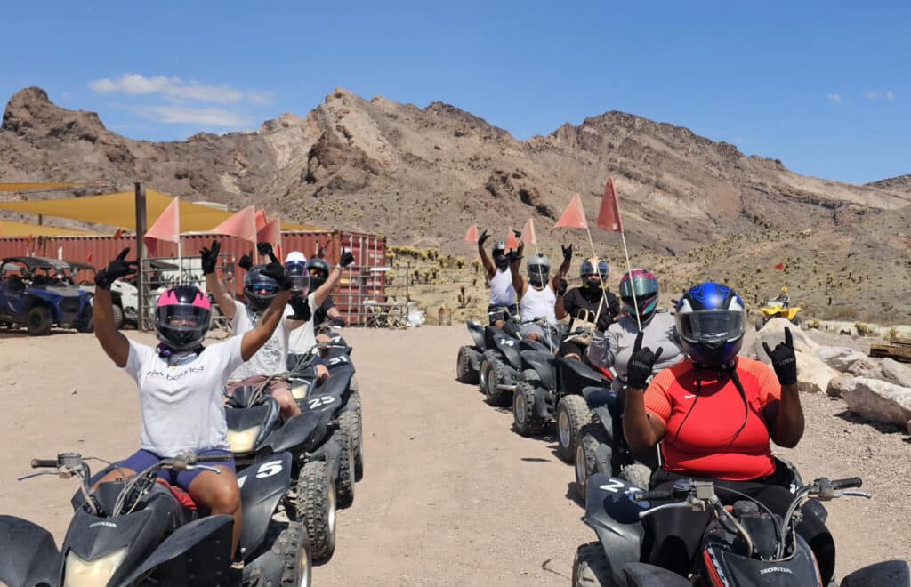 Adventurers on ATVs in Nevada’s rocky desert near Las Vegas, ready for an exciting off-road ATV tour under clear blue skies.