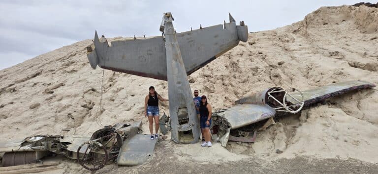 Three people by a plane wreck on a rocky Nevada hillside near Las Vegas, perfect for ATV tours and Ghost Town sightseeing.