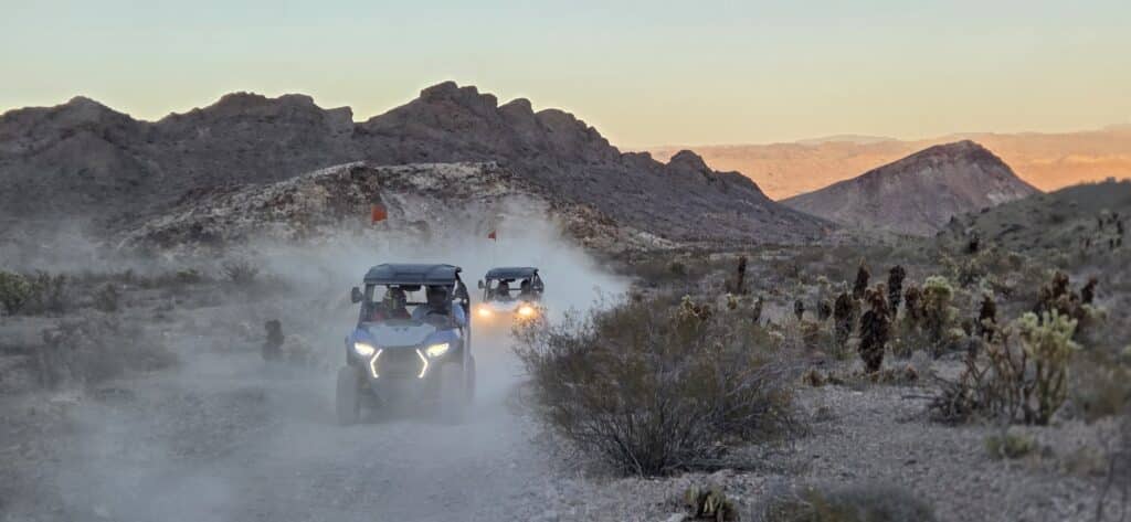 ATV tours in Nevada: two off-road vehicles on a dusty desert trail near rocky hills at sunset close to Las Vegas and the Colorado River.