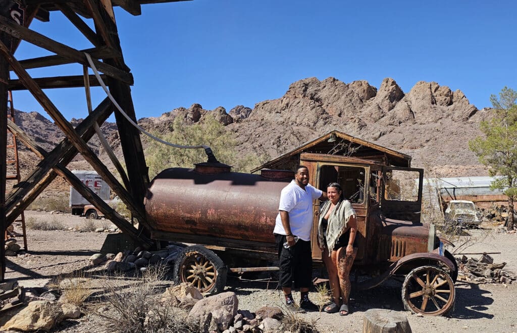 Smiling at a vintage truck in a Nevada ghost town near Las Vegas, perfect for ATV tours and Colorado River sightseeing.