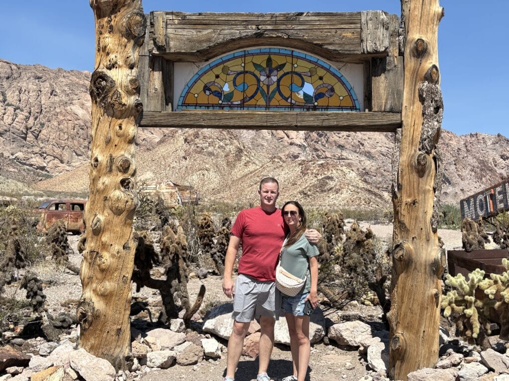 A couple poses under a rustic arch with stained glass amid cacti and rocks near Las Vegas, Nevada, overlooking the Colorado River.