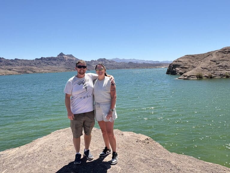 Smiling couple by turquoise Colorado River near Las Vegas, Nevada, mountains behind—perfect spot for ATV tours or Ghost Town sightseeing.