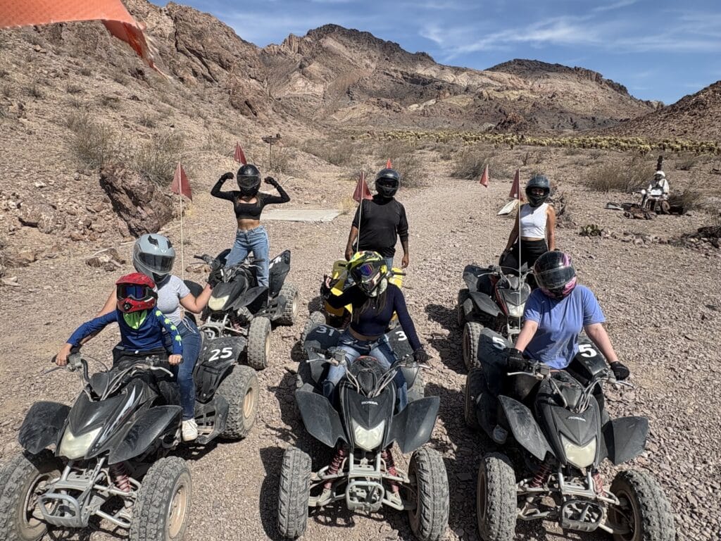 Group on black ATVs enjoys a Nevada desert trail ride near Las Vegas, mountains behind, part of thrilling ATV tours adventure.