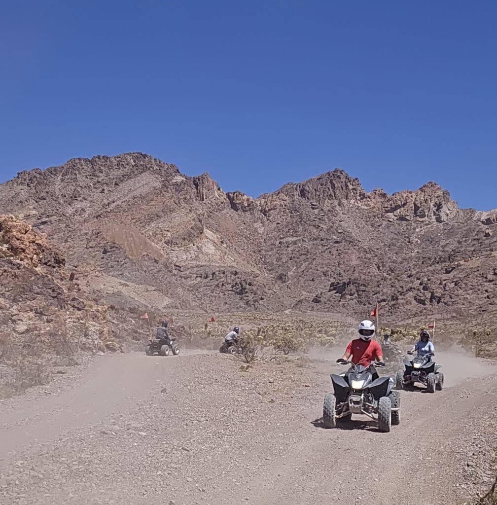 ATV riders on a Nevada desert trail near Las Vegas, exploring rocky mountains on an exciting off-road tour under clear blue skies.