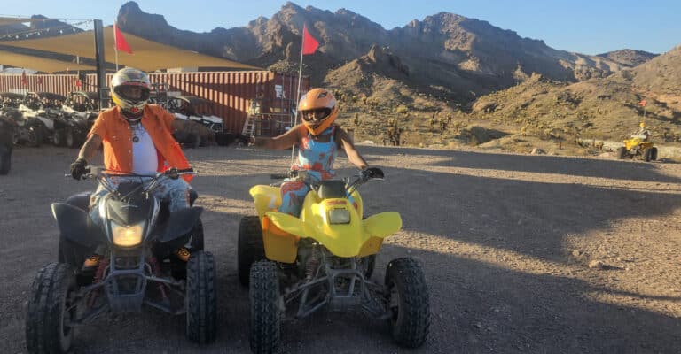 Riders in helmets on black and yellow ATVs in Nevada, ready for a Las Vegas ATV tour near scenic mountains and desert views.