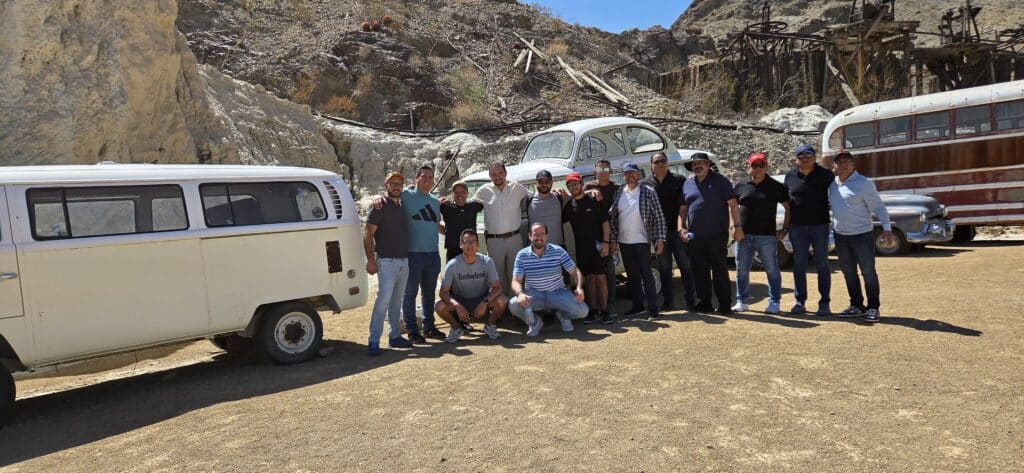 Friends pose by a vintage van, classic car, and old bus in a Nevada ghost town near Las Vegas and the Colorado River.