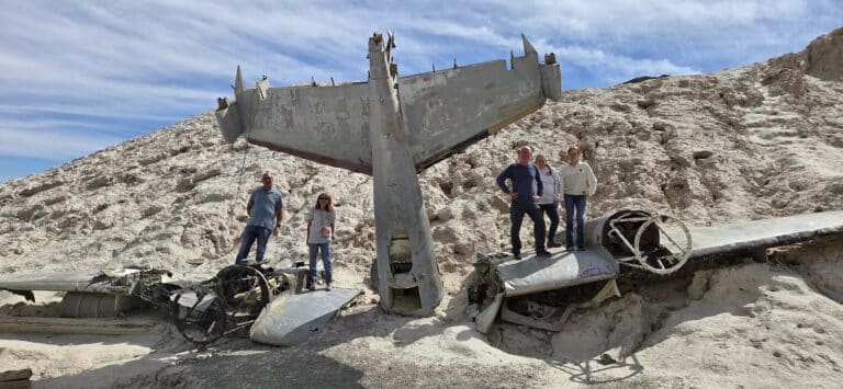 Adventurers explore a wrecked plane near Nevada’s rocky sands, perfect for Las Vegas ATV tours and Ghost Town sightseeing.