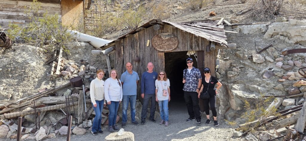 Group at historic Nevada mine entrance near Las Vegas, surrounded by desert on a sunny day during a Ghost Town sightseeing tour.
