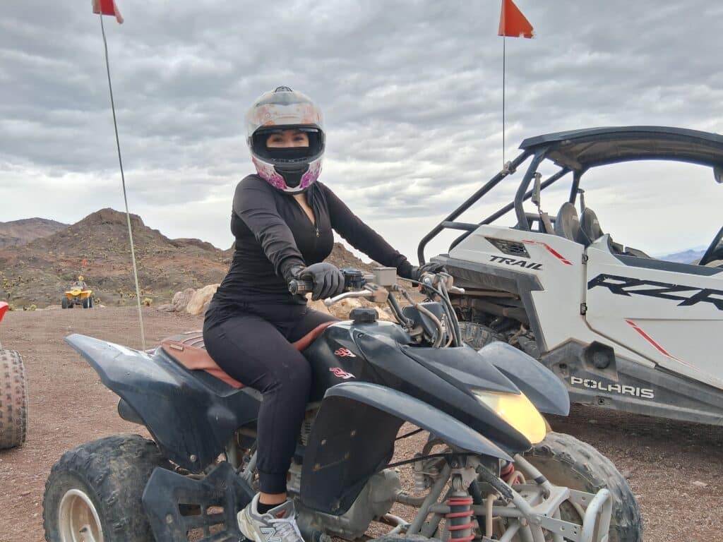 Rider in black gear on ATV explores Nevada desert near rocky hills, off-road vehicle, and cloudy sky—perfect for Las Vegas ATV tours.