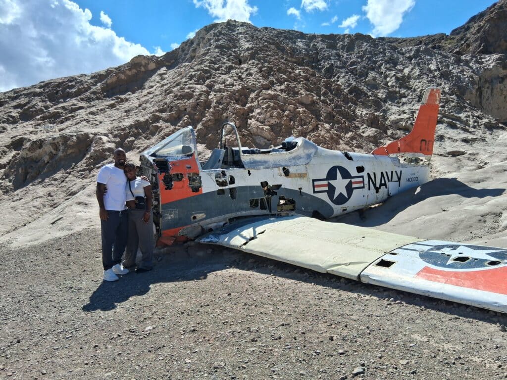 Smiling couple by a Navy plane wreck in the Nevada desert near Las Vegas, perfect for ATV tours and Ghost Town sightseeing.