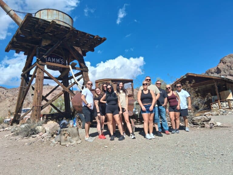 Smiling group at Nevada ghost town by HAMMS water tower near Las Vegas, with desert views—perfect for ATV tours and sightseeing.