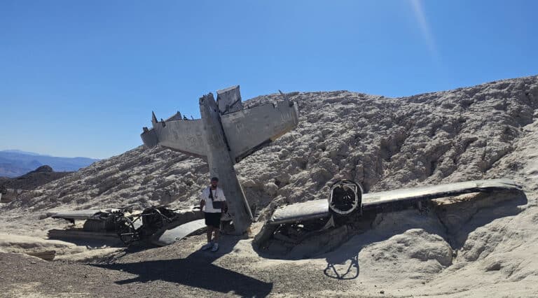 Adventurer explores crashed airplane wreckage in Nevada desert near Las Vegas, perfect for ATV tours and RZR off-road rides.