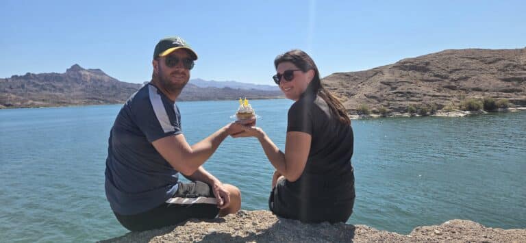 Couple enjoys Nevada’s Colorado River views on a rocky ledge, sharing a cupcake after an ATV tour near Las Vegas.