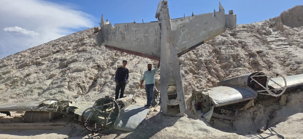 Two people explore a crashed plane near Las Vegas in Nevada’s desert, popular for RZR rides and Ghost Town tours.