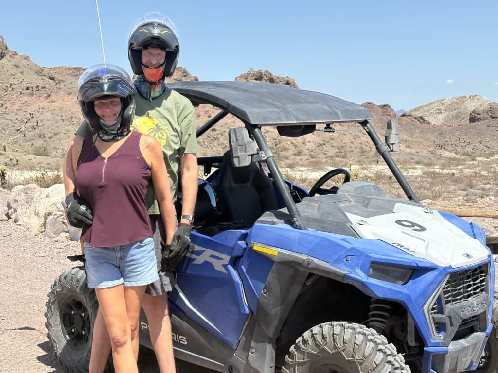 Adventurers in helmets by a blue Polaris RZR during an ATV tour in Nevada’s rocky desert near the Colorado River.