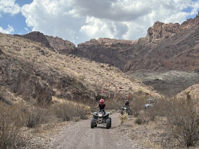 ATV riders explore a rocky desert trail near Las Vegas, Nevada, with scenic mountains—perfect for an adventurous ATV tour.