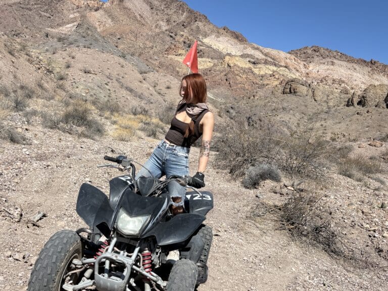 Woman with long brown hair by black ATV in Nevada desert near Las Vegas, perfect for RZR off-road tours and ghost town sightseeing.