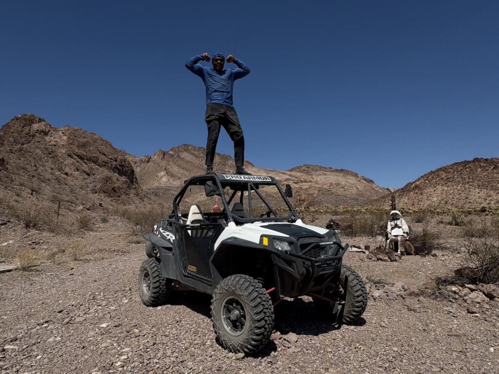 Adventurers enjoy an ATV tour near Las Vegas in Nevada’s rocky desert, with mountains and campfire under blue skies.