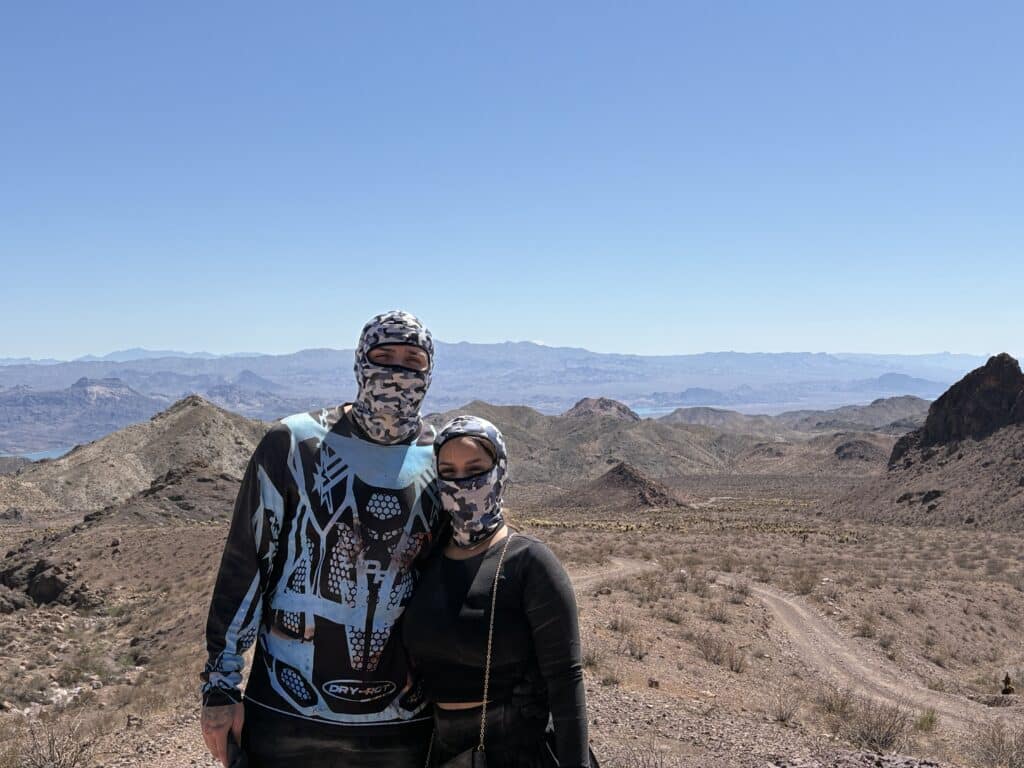 Two people in patterned masks and outdoor gear pose in a Nevada desert near Las Vegas, ideal for ATV tours and RZR off-road rides.