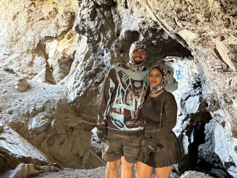 Adventurers in outdoor gear explore a sunlit cave near Las Vegas, Nevada during an ATV tour by the Colorado River.