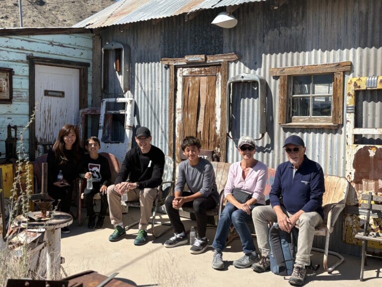 Visitors relax on benches outside rustic Nevada ghost town buildings, perfect for Las Vegas sightseeing or Colorado River ATV tours.