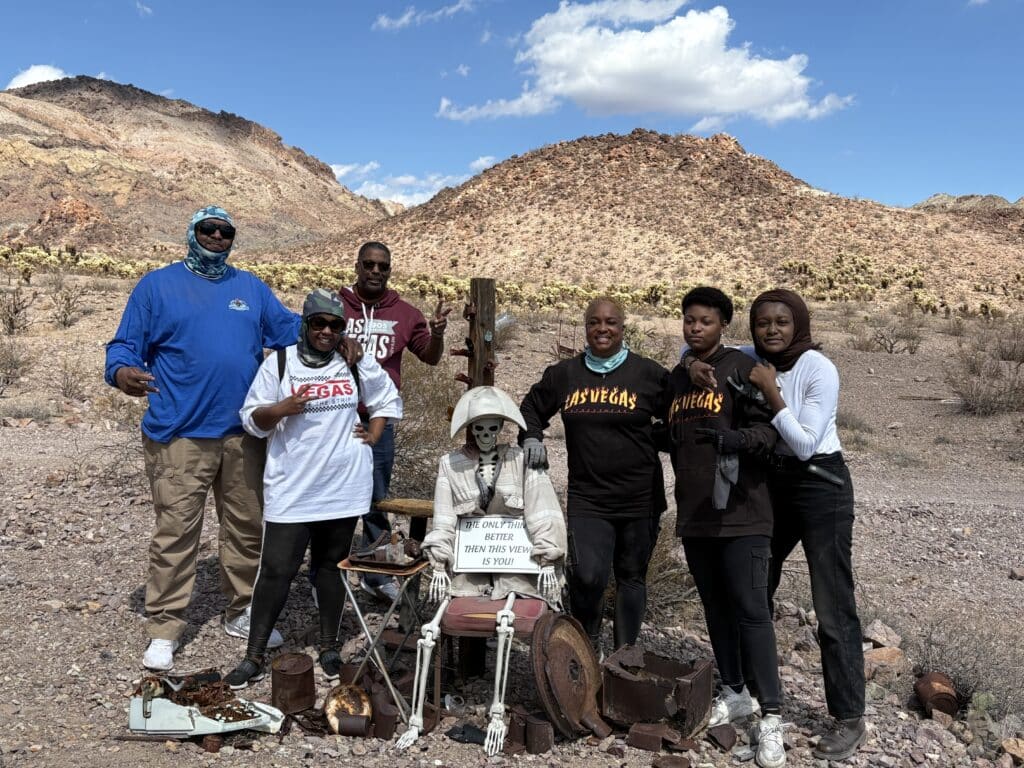 Group poses in a Nevada desert ghost town near Las Vegas, skeleton display—fun stop on ATV or RZR tour by the Colorado River.