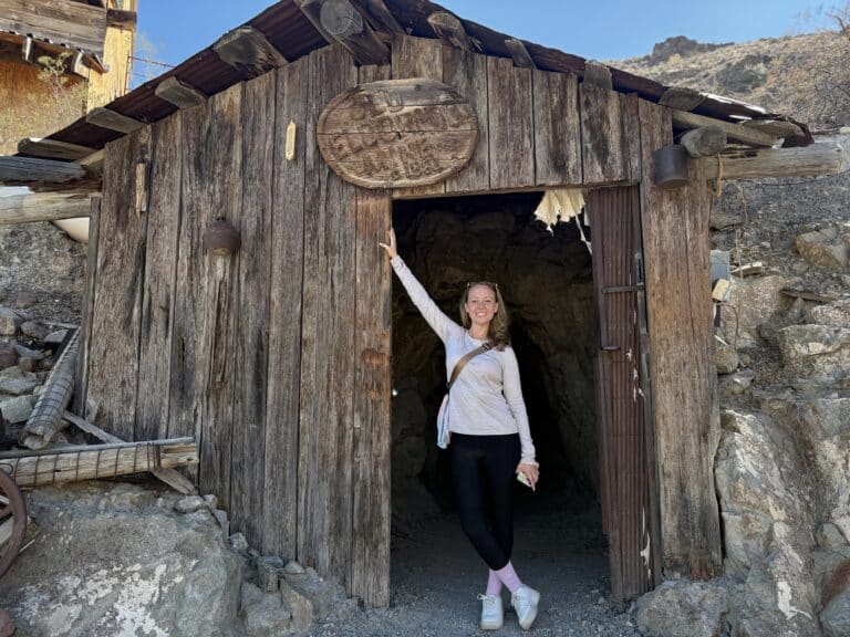 Woman poses smiling at old mine shack near Las Vegas, Nevada, perfect for ATV tours and Ghost Town sightseeing adventures.