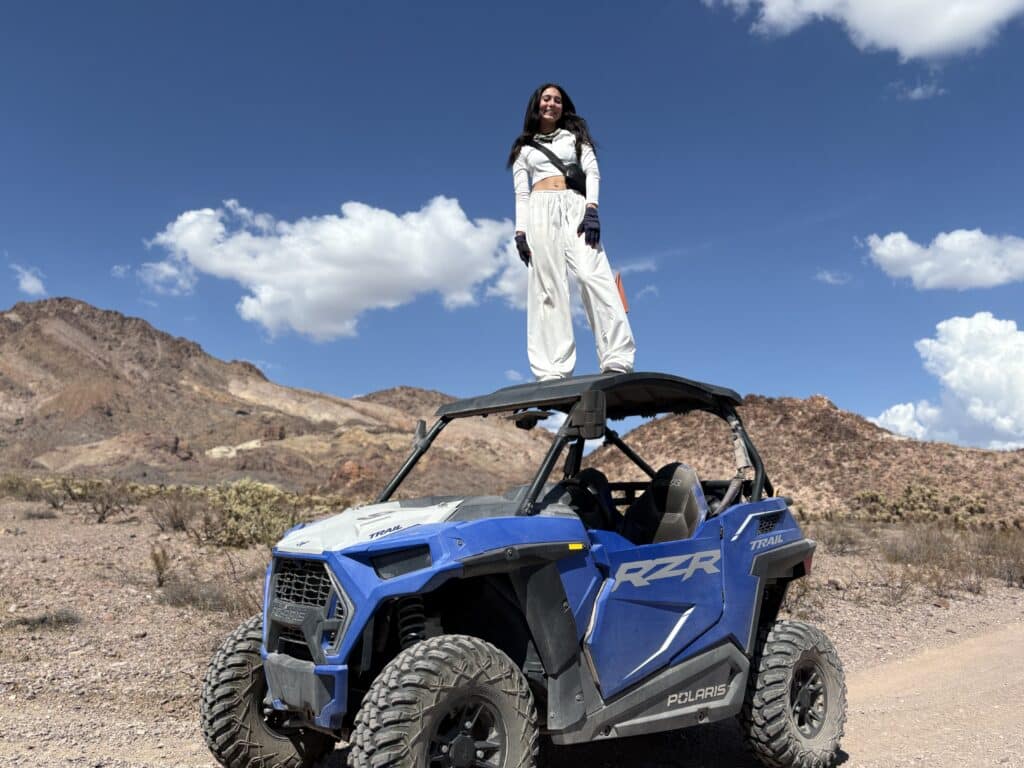 Confident woman in white on a blue Polaris RZR in Nevada desert, perfect for Las Vegas ATV tours and RZR off-road adventures.