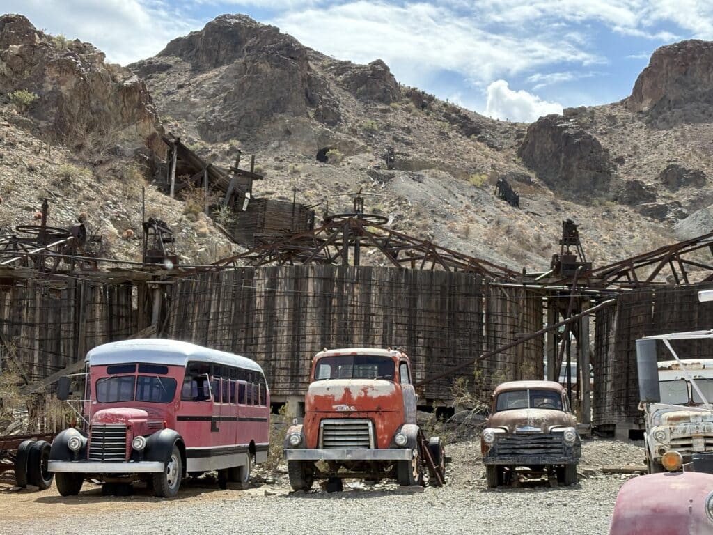 Vintage red and brown trucks by mining relics near Las Vegas, Nevada—perfect for Ghost Town sightseeing and ATV tours.