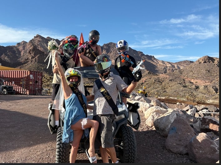 Five helmeted riders pose with a bouquet on an ATV in Nevada’s desert near Las Vegas, celebrating their thrilling ATV tour.
