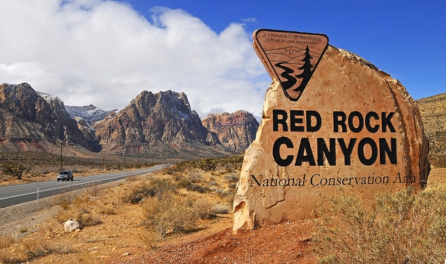 Red Rock Canyon sign near Las Vegas, Nevada, with desert mountains—a top spot for ATV tours and sightseeing adventures.