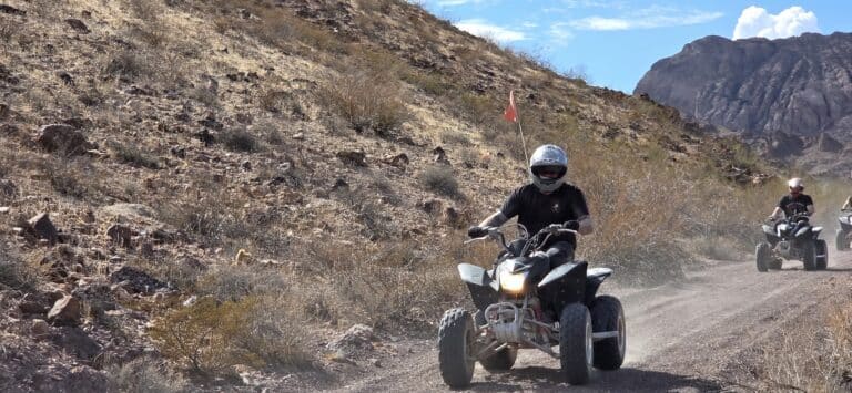 ATV riders explore a dusty Nevada desert trail near Las Vegas, surrounded by rocky hills—perfect for ATV tours.