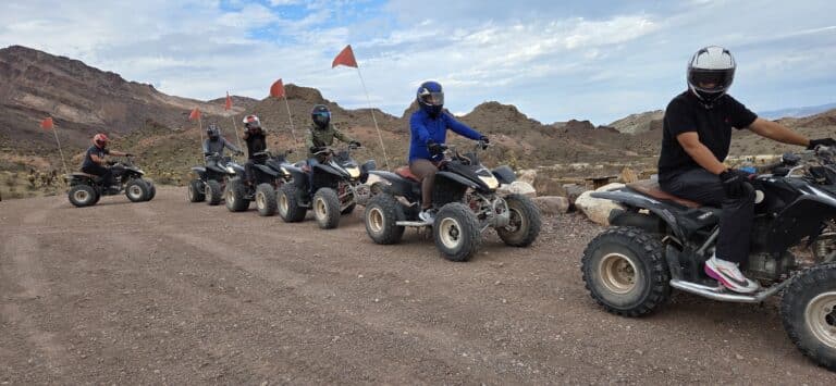 Group rides ATVs with red flags on a desert trail near Las Vegas, Nevada, enjoying an exciting off-road ATV tour.