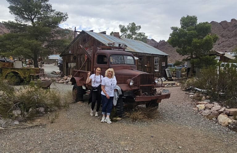 Two women by a rusty pickup near a Nevada ghost town, perfect for ATV tours and sightseeing close to Las Vegas and Colorado River.