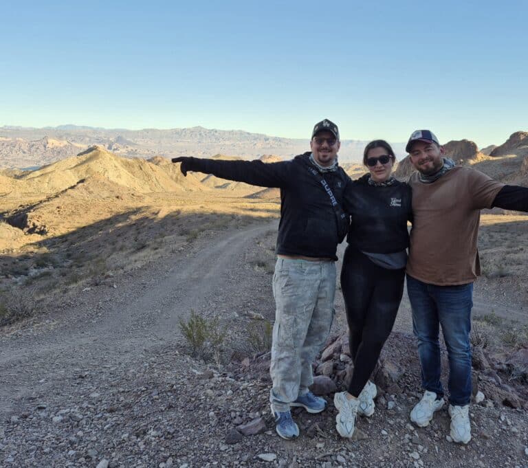 Smiling friends on a Nevada desert trail near Las Vegas with mountains, ready for ATV tours or Colorado River sightseeing.