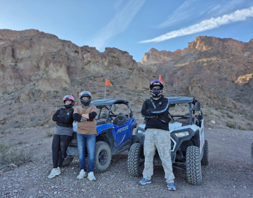 Adventurers in helmets pose by ATVs in a Nevada desert near Las Vegas, ready for RZR off-road rides and Ghost Town tours.