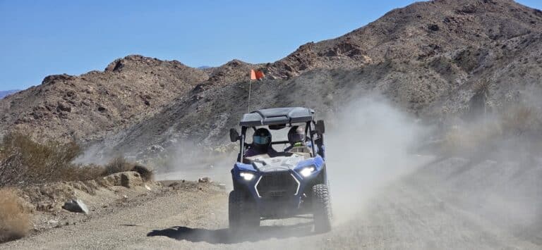 Blue off-road ATV with two riders on a dusty Nevada trail near Las Vegas, perfect for thrilling ATV tours and RZR adventures.