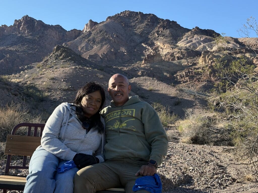 Smiling couple on a bench near Nevada's rocky mountains, desert views, ideal for Las Vegas ATV tours or Colorado River adventures.