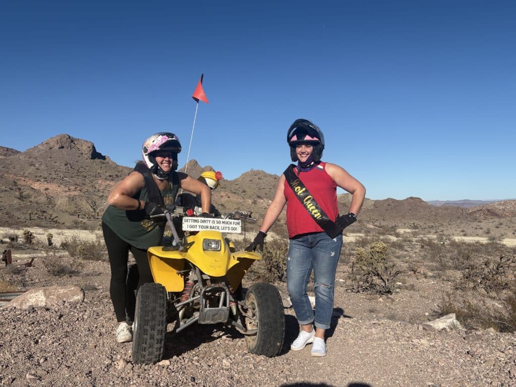 Smiling duo enjoy an ATV tour near rocky hills in Nevada desert, close to Las Vegas and the Colorado River, under clear skies.