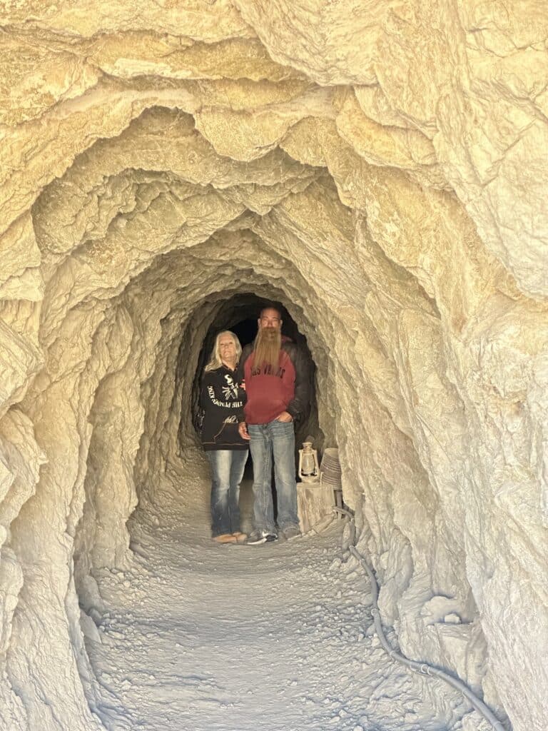 Adventurers in a rocky Nevada tunnel near the Colorado River, with lantern, ready for Las Vegas ghost town or ATV tours.