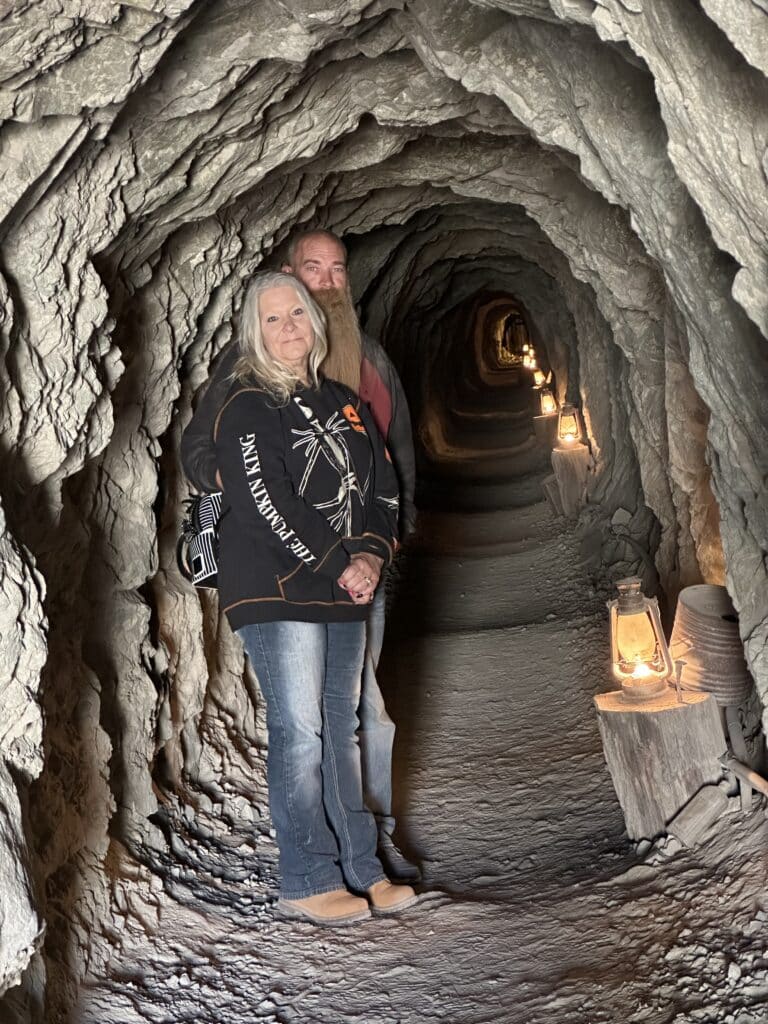 Smiling couple in a narrow, lantern-lit Nevada tunnel near the Colorado River—perfect for Las Vegas ATV and ghost town tours.