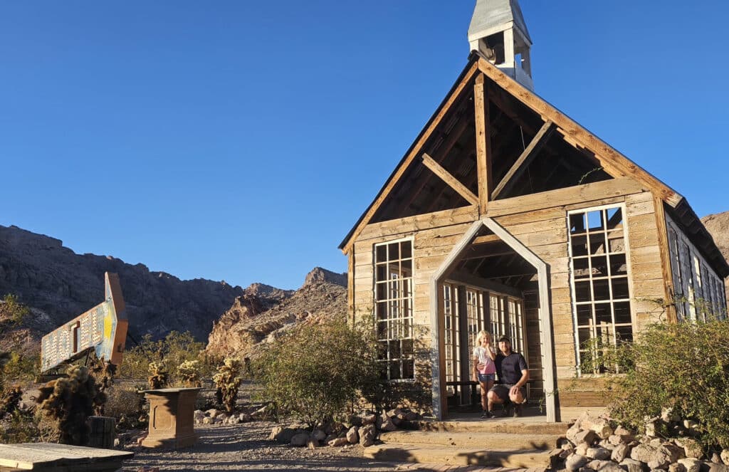 A man and child in a rustic wooden chapel near Las Vegas, Nevada, with desert views—perfect for Ghost Town sightseeing.
