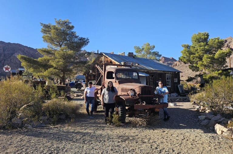 Visitors pose by a rusty truck at a Nevada ghost town near the Colorado River, ideal for ATV tours or RZR off-road adventures.
