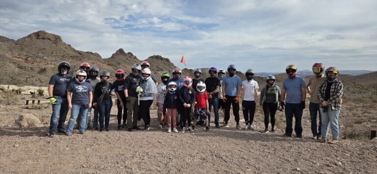 Group on Nevada rocky terrain wearing helmets and casual clothes, ready for an ATV tour near the Colorado River by Las Vegas.