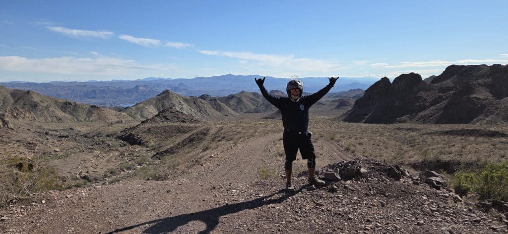 Rider in black celebrates on a rocky Nevada trail near Las Vegas, mountains behind—perfect for RZR ATV tours and desert adventure.