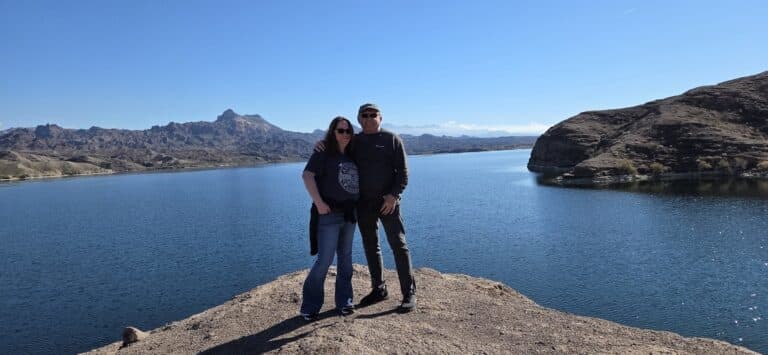A couple smiles atop a rocky outcrop by the Colorado River near Las Vegas, Nevada, enjoying scenic views and outdoor adventure.